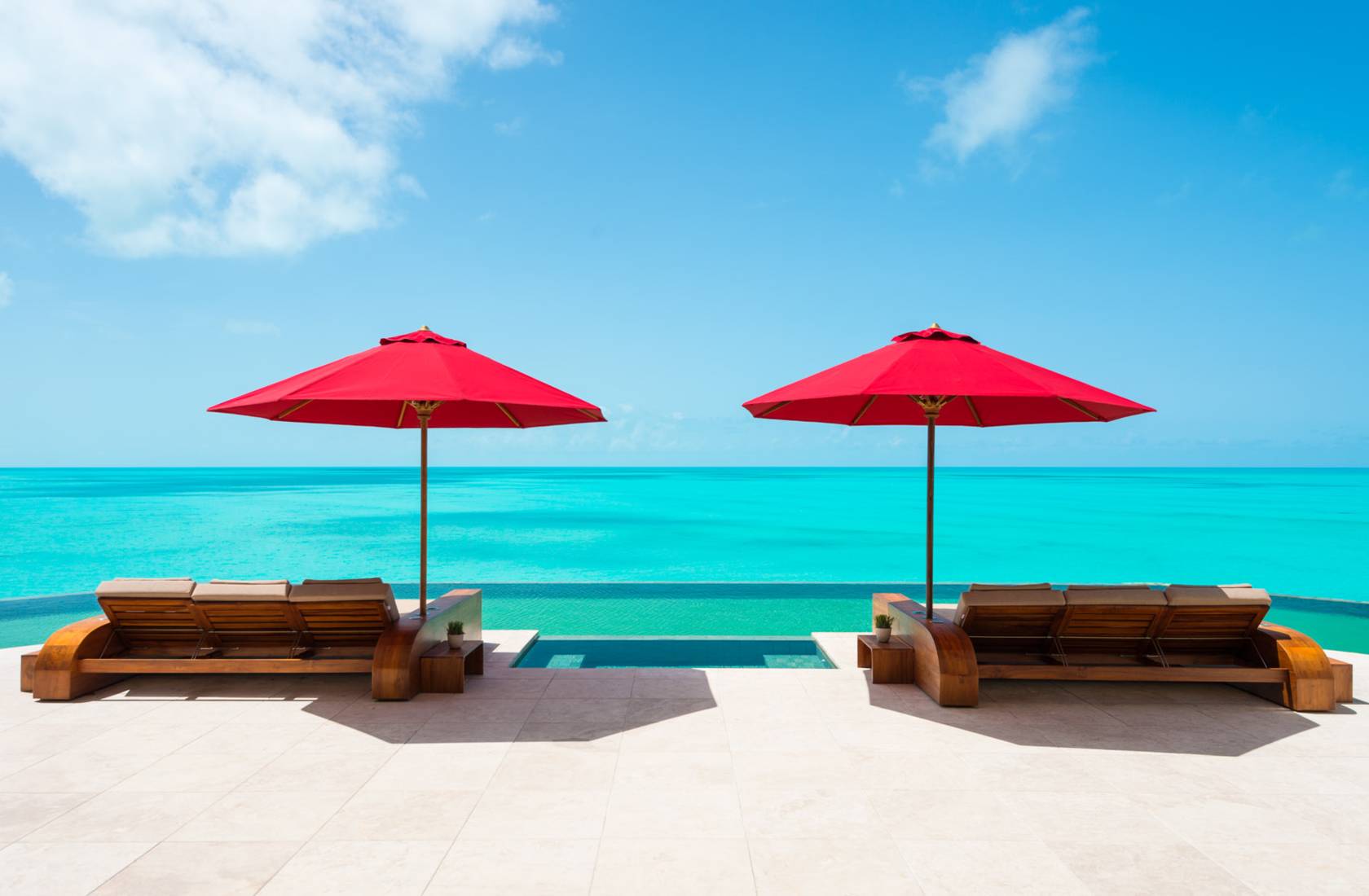 Villa Balinese poolside loungers and umbrellas overlooking Turks and Caicos shore